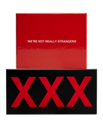 A glossy red box reading "We're Not Really Strangers" sits stacked on a wider black box with three large red X letters.