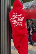 Red sweatsuit with white text on back reading "you deserve every good thing that happens to you," featuring a hoodie and matc