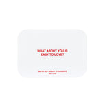 White rounded card with red text reading "What about you is easy to love?" and "We're not really strangers self love".