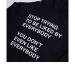 Black hoodie with white text reading "Stop Trying To Be Liked By Everybody You Don't Even Like Everybody"