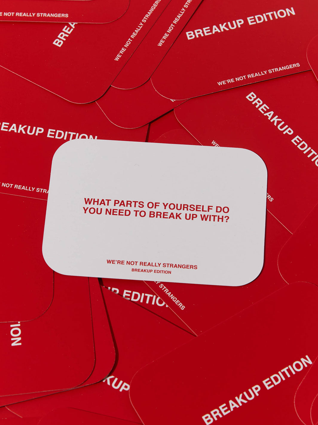Multiple red cards with "Breakup Edition" text and a white card displaying "What parts of yourself do you need to break up wi