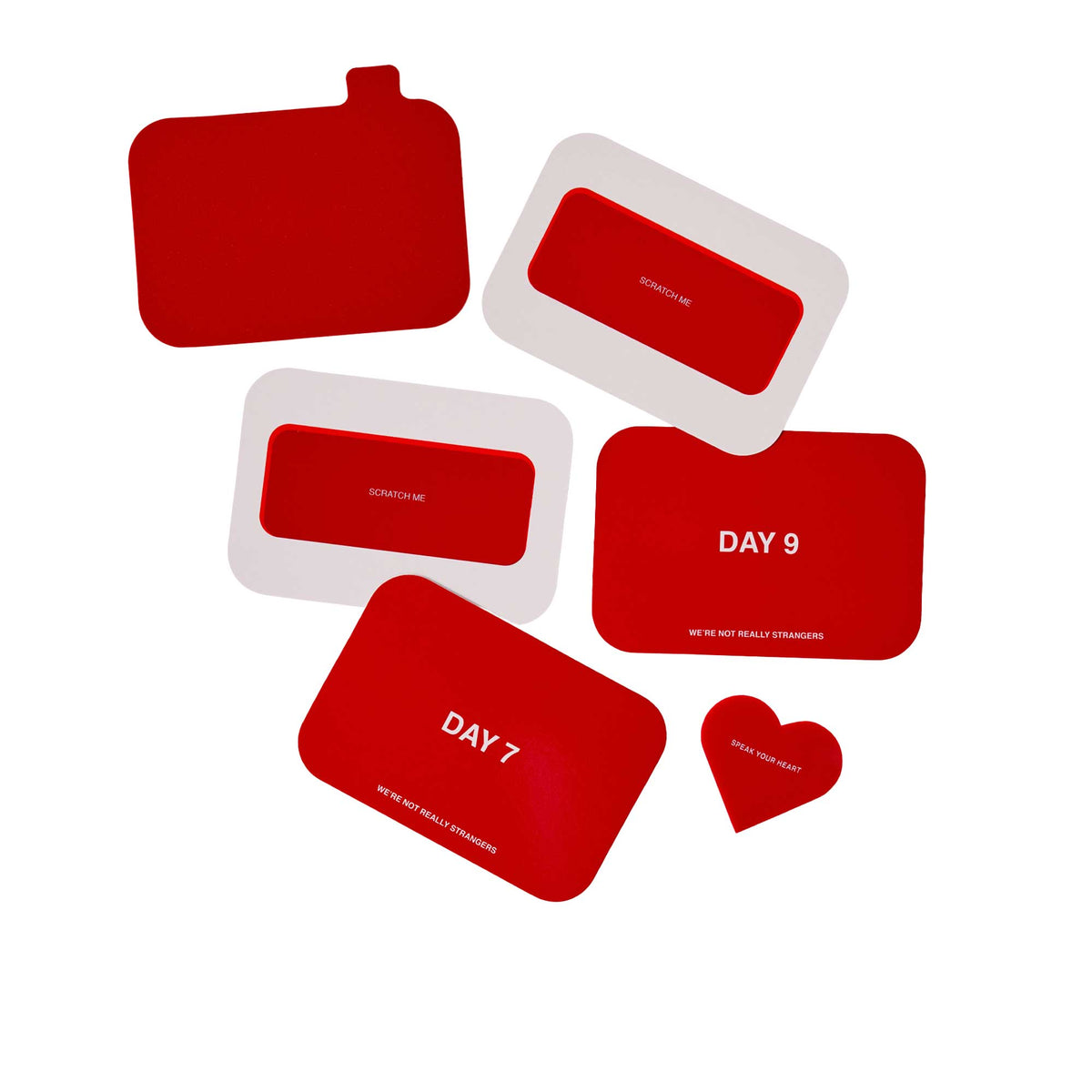 Collection of red scratch-off cards and pouches in various shapes including rectangles and a heart, with text printed on surf