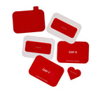 Collection of red scratch-off cards and pouches in various shapes including rectangles and a heart, with text printed on surf