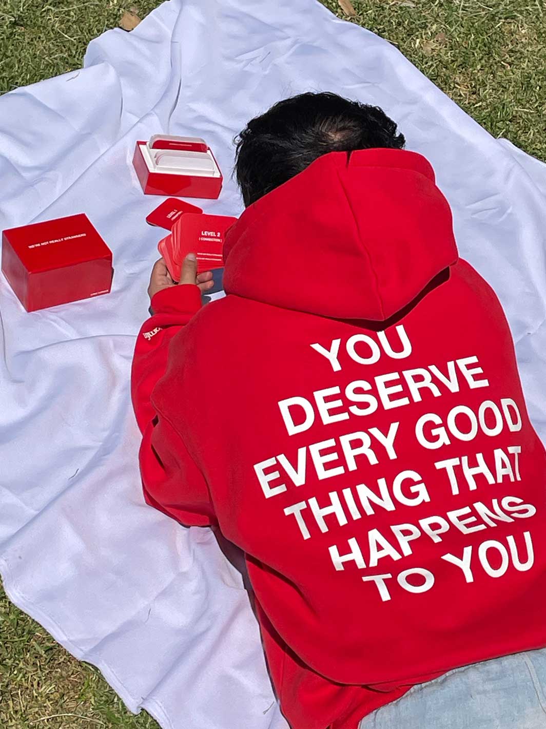 Red hoodie with white text on back reading "You deserve every good thing that happens to you," displayed flat on white fabric