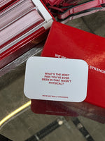 White card with red text reading "What's the most pain you've ever been in that wasn't physical?" alongside red game box and 
