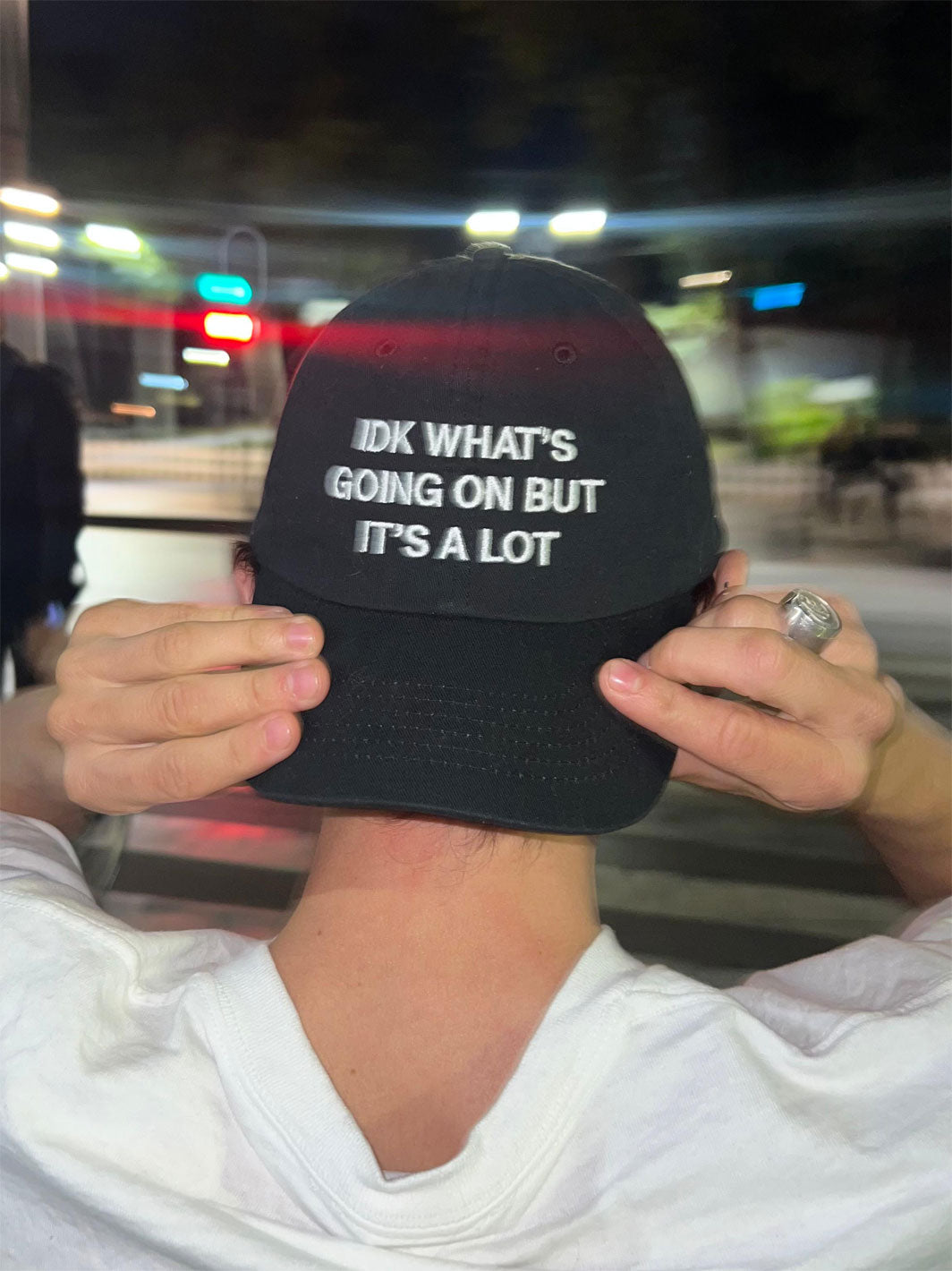 Black dad hat with white text reading "IDK WHAT'S GOING ON BUT IT'S A LOT" on the crown.