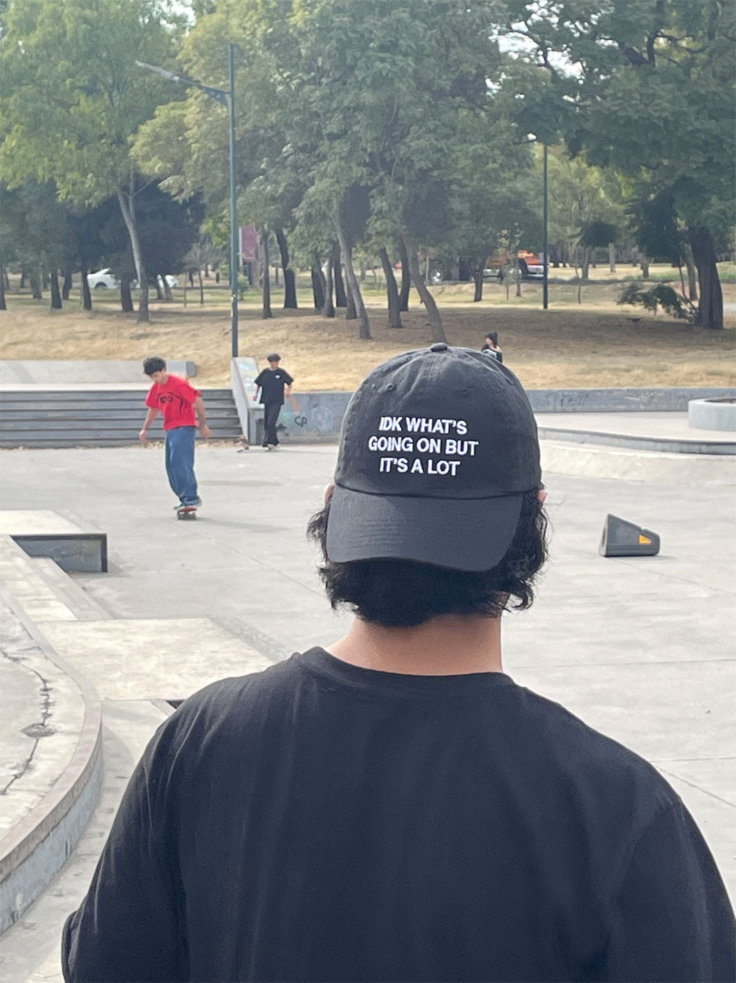 Black dad hat with white text reading "IDK WHAT'S GOING ON BUT IT'S A LOT" on the front.