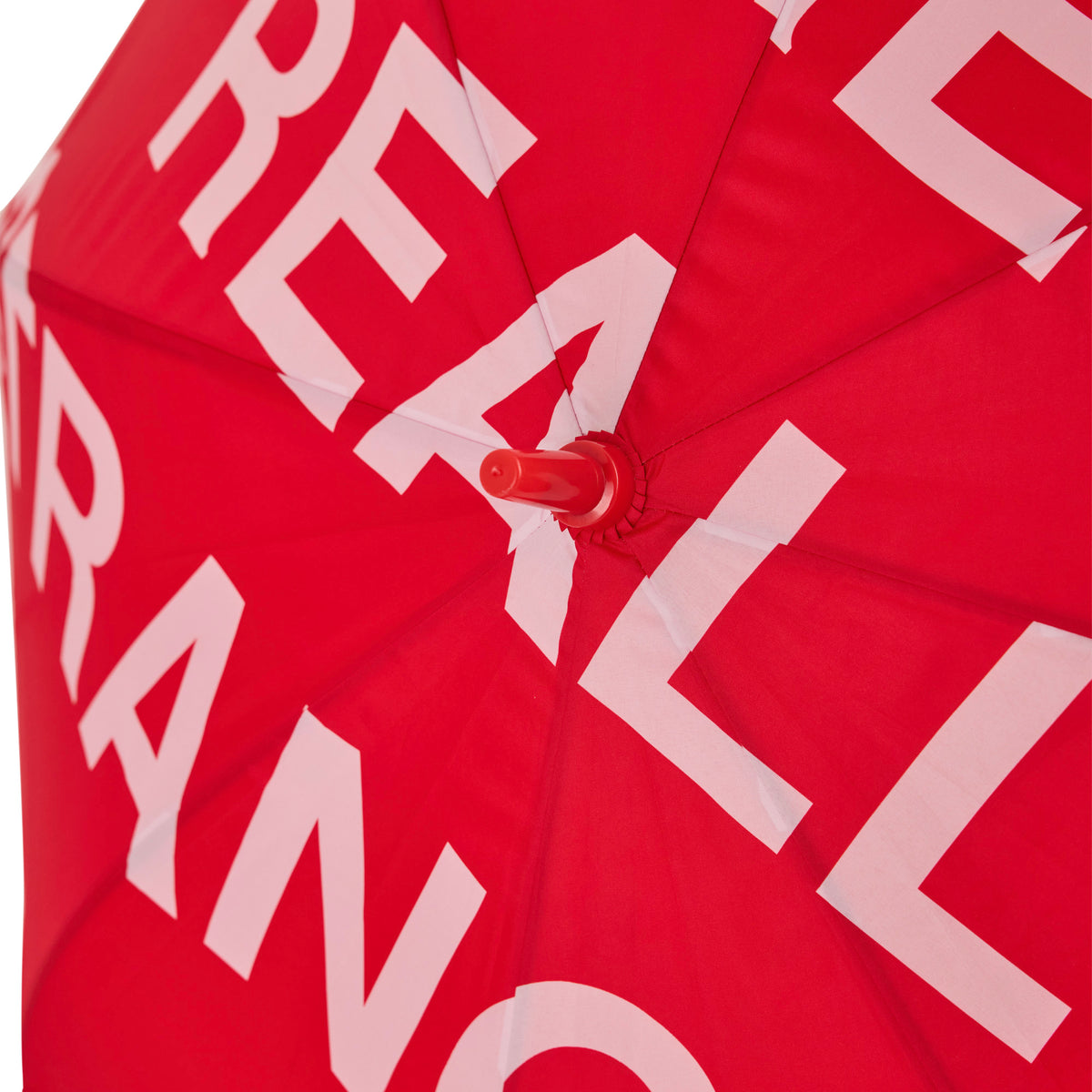 Red umbrella with pink and white geometric text pattern and red handle.