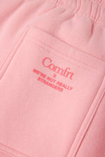 Pink sweatpants with "Comfrt x We're Not Really Strangers" embroidered text on front pocket.