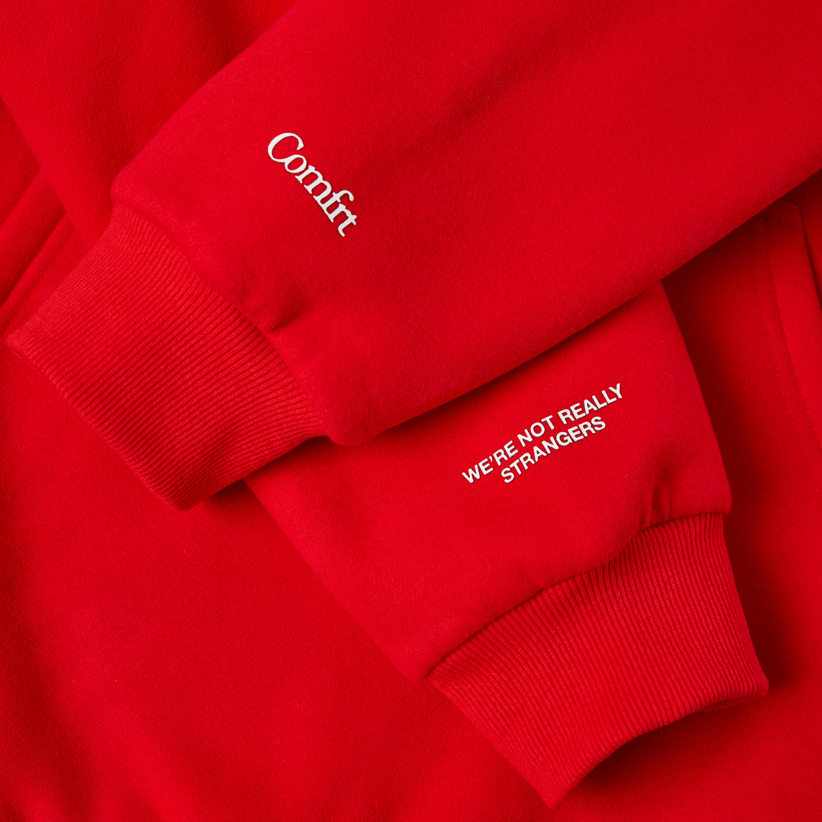 Red crewneck sweatshirt and sweatpants set with white embroidered logos and text on chest and leg.