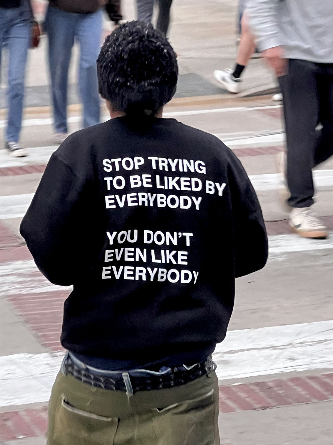 Black crewneck sweatshirt with white text reading "Stop Trying to Be Liked by Everybody You Don't Even Like Everybody" on bac