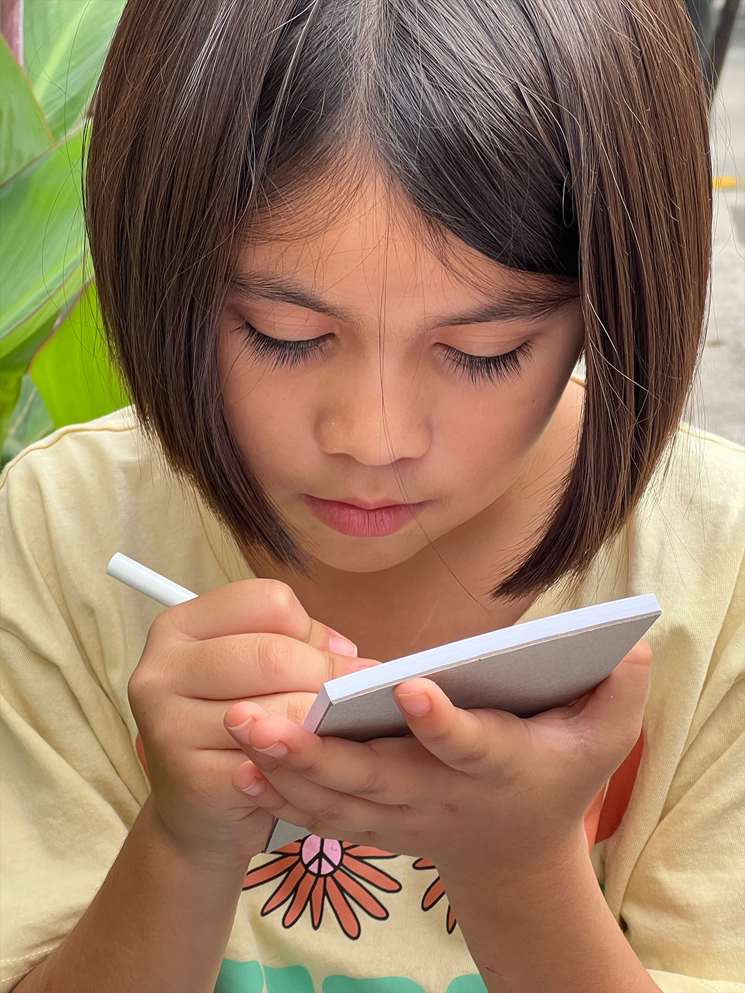 We're Not Really Strangers Kids Edition. Kid writing with the colored pencil on notepad.