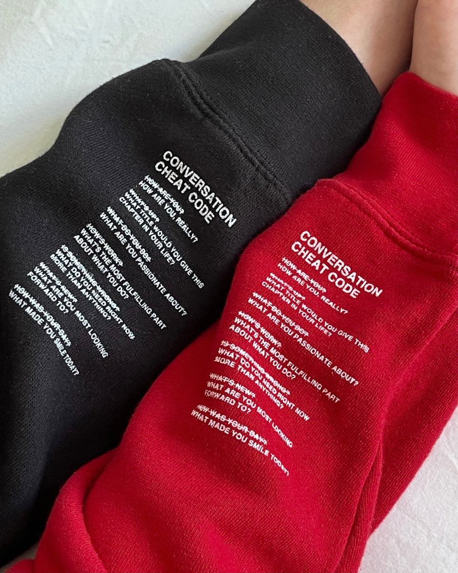 We're Not Really Strangers red and black conversation cheat code crewnecks zoomed in view of sleeve detail.