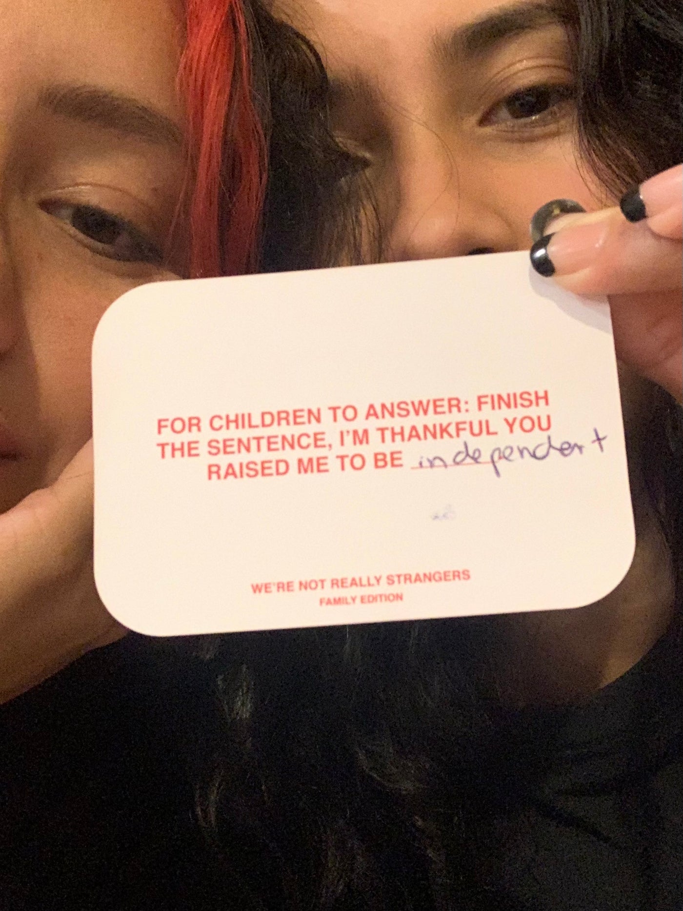 We're Not Really Strangers two people holding up Family Edition card reading "For children to answer: finish the sentence, I'm thankful you raised me to be___" with handwriting  on card reading "independent."