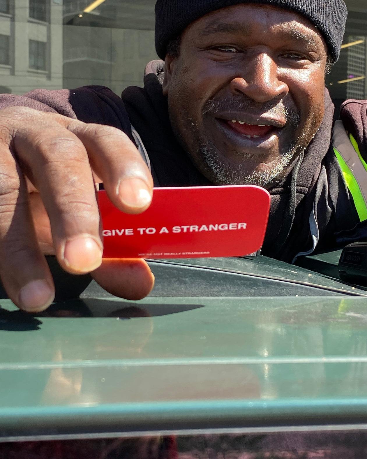 We're Not Really Strangers Give to a Stranger Pack. Person holding up Give to a Stranger card, back view of red card with white font reading "Give to a Stranger."