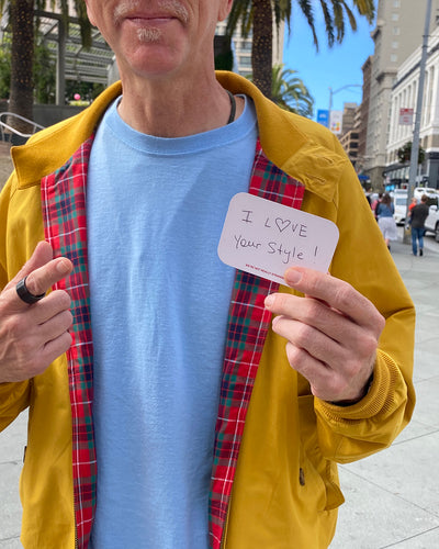 We're Not Really Strangers Give to a Stranger Pack. Person outdoors holding a card reading (in hand-written text) "I Love your style!"