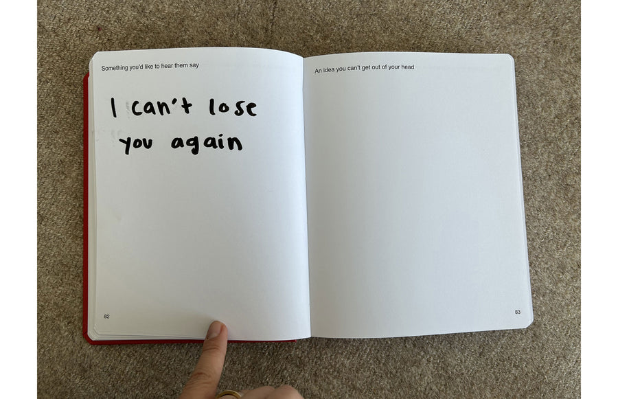 We're Not Really Strangers Journal. Front facing view of someone holding down one of the journal pages with prompt 